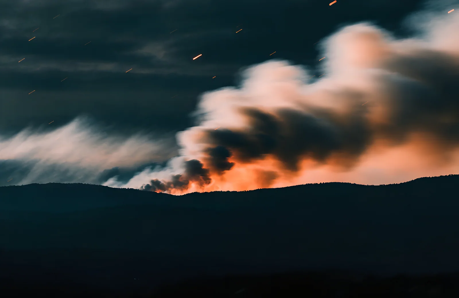 Smoke and active fire moving across a wildland ridge