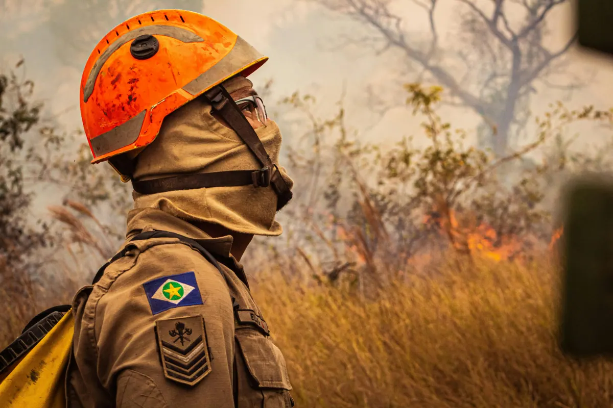 Solo firefighter in profile with smoke and fire behind him